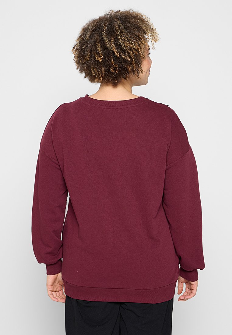 Felpa bordeaux con maniche lunghe, scollo rotondo e vestibilità morbida. Realizzata in un tessuto morbido con una texture liscia.