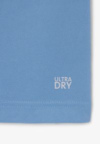 Lichtblauwe textuurstof met witte gestikte zoom en de tekst "ULTRA DRY" gedrukt bij de onderrand.