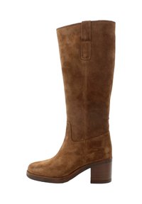 Stivale in suede marrone al ginocchio con punta quadrata e tacco impilato. Caratterizzato da una cucitura e un tab per una vestizione più facile.