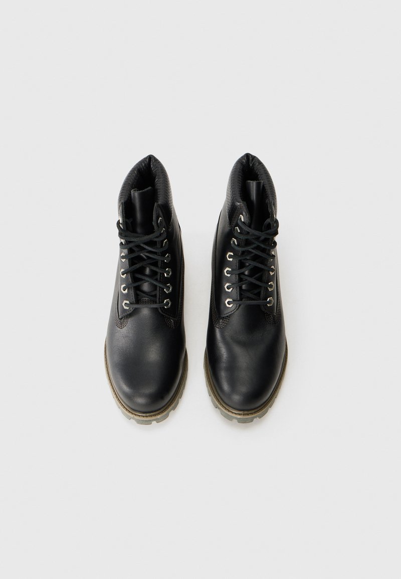 Schwarze Lederstiefel mit Knöchelhöhe, strukturiertem Innenfutter, silbernen Ösen und schwarzen Schnürsenkeln. Mit einer robusten Gummisohle für verbesserten Halt.