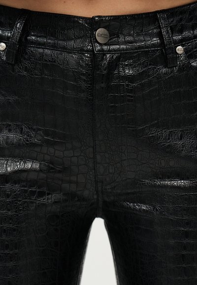 Μαύρο παντελόνι από συνθετικό δέρμα με υφή κροκοδείλιου δέρματος, κούμπωμα με κουμπιά μπροστά και ορατές θηλιές για ζώνη στο ύψος της μέσης.