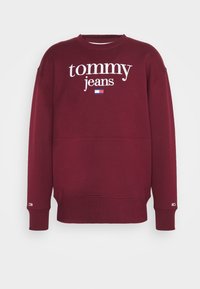 Felpa bordeaux con il testo "tommy jeans" bianco, polsini e vita a coste. Presenta un piccolo logo a bandiera sulla manica. Tessuto morbido.