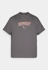 Szary bawełniany t-shirt z krótkimi rękawami i okrągłym dekoltem. Z nadrukiem graficznym z tekstem i skrzydłami w kontrastujących kolorach.