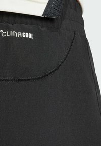 Svarta träningsshorts i ett mjukt, lätt material med en logotyp som säger "CLIMACOOL" och synliga sömmar detaljerade vid midjan.