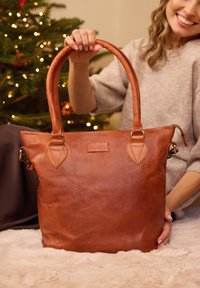 Brown leather tote bag with a textured surface, featuring a stitched design, rounded handles, and metal hardware accents.
