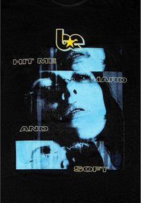 Czarna koszulka z niebieskim graficznym wzorem twarzy oraz napisem "HIT ME HARD AND SOFT" w żółtym i białym kolorze.