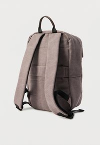 Γκρι υφασμάτινο σακίδιο με στρογγυλεμένο σχήμα, επενδεδυμένους ιμάντες και δερμάτινη λαβή στην κορυφή. Διαθέτει οριζόντιο ράμμα και ρυθμιζόμενους ιμάντες.