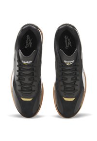 Tênis atléticos pretos com um cabedal de couro liso, detalhes texturizados em cinza escuro, detalhes em dourado e sola de borracha de cor caramelo. Design com atacadores.