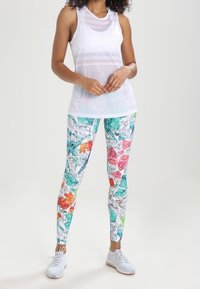 White sleeveless athletic top with a subtle striped pattern, paired with colorful leggings featuring a gemstone print in varied shapes and hues.