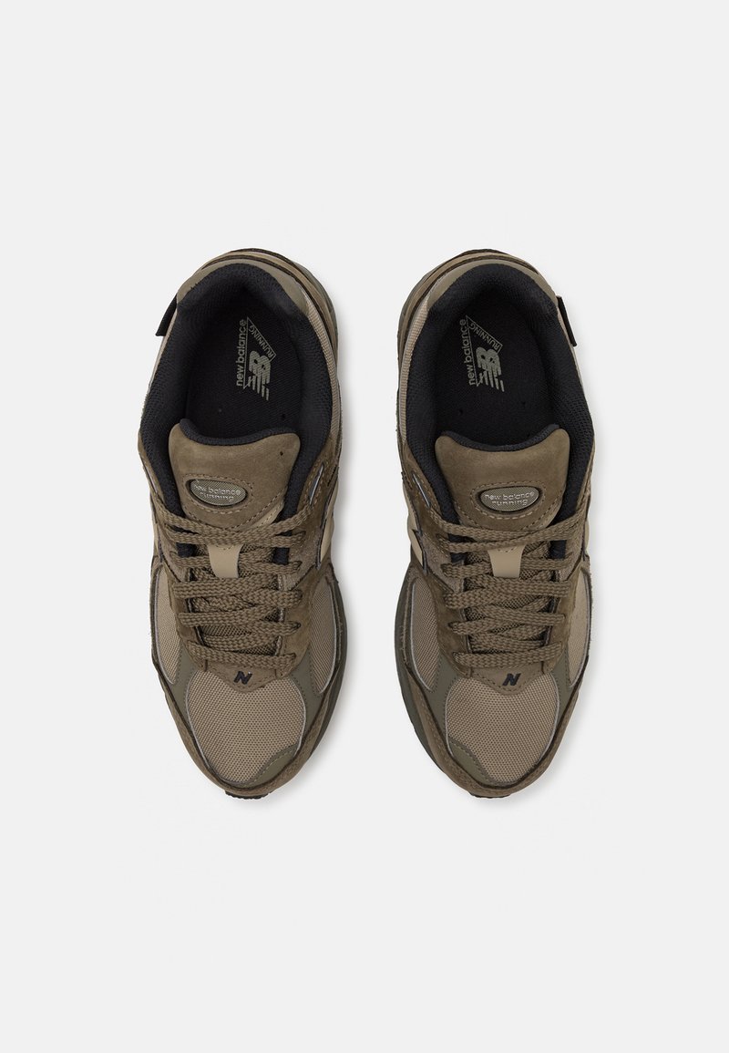 Chaussures de sport marron en matériau mesh et suede. Elles disposent d'une semelle robuste, d'une languette rembourrée et d'un système de laçage. Logo visible sur le côté.