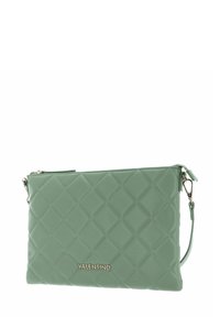 Sac bandoulière vert en similicuir matelassé avec garnitures dorées, doté d'une fermeture éclair et d'un logo de marque sur le devant.