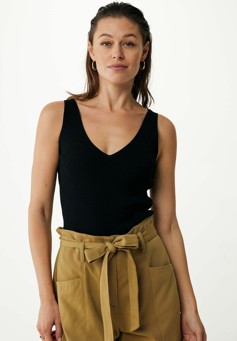 Schwarzes, geripptes Tanktop mit V-Ausschnitt, kombiniert mit hoch taillierten, olivgrünen, mit Gürtel versehenen Hosen mit Seitentaschen.