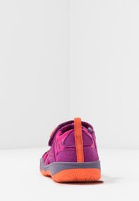 Zapato infantil en púrpura y naranja con textura de ante, correa ajustable y suela de goma con un diseño estampado en la parte trasera.
