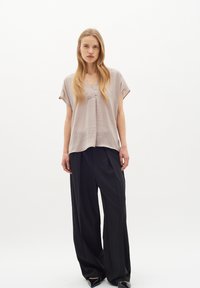 Top grigio a maniche corte e scollatura a V con un fit rilassato, abbinato a pantaloni neri a gamba larga. Entrambi i capi presentano trame morbide e design semplici.