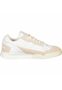 Vita och beige låga Adidas-sneakers med mockadetaljer, snörning fram och gummisula, visade från sidan mot en vit bakgrund.