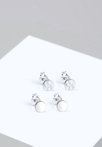 Sterling ezüst beszúrós fülbevalók, egy áttetsző és egy tükröződő kör alakú dizájnnal. Minimalista fémrész és átlátszó díszítőelemek jellemzik.