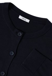 Marineblauwe cardigan met geribbelde kraag en zak. Bevat een sluiting met vijf knopen, een gladde textuur en een label met de merknaam "CECiL".