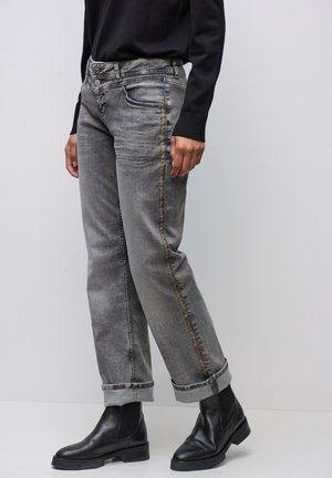 Grå denimjeans med rak passform, som har en subtil glans och guldfärgade dekorativa sömmar längs sidan, bars med svarta ankelstövlar.