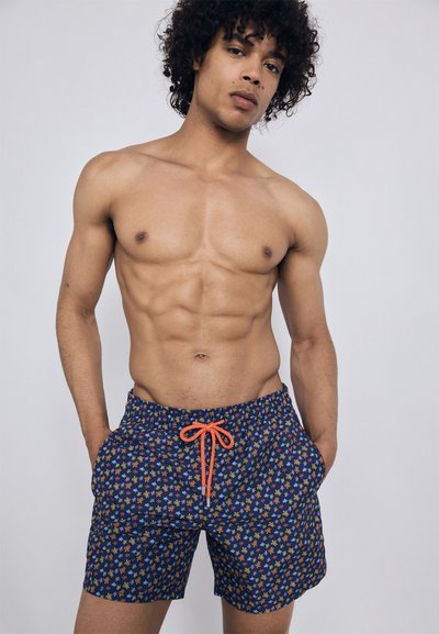 Bañador con fondo azul y un patrón floral en naranja, amarillo y blanco. Cintura elástica con cordón de ajuste naranja.
