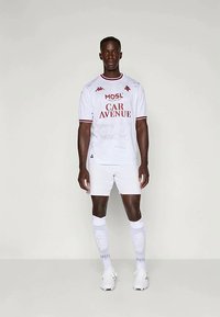 Valge jalgpallivormi särk punaste aktsentidega, kus on välja toodud "MOSL" ja "CAR AVENUE", koos valgete lühikeste pükste ja sokkidega, millel on tekstuurilised mustrid.