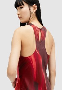 Sleeveless red dress with a smooth, glossy fabric, featuring a keyhole back detail and abstract pattern blending darker and lighter reds.