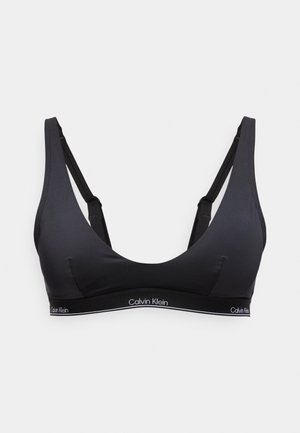 Musta Calvin Klein -bralette säädettävillä olkaimilla ja rinnan alla olevalla brändätyllä elastisella nauhalla, edestä katsottuna vaalealla taustalla.