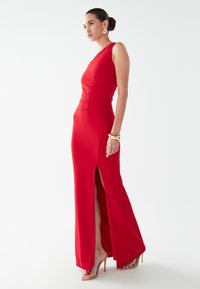 Červené, priliehavé šaty s jedným ramienkom, bočným rozparkem a hladkým, textúrovaným materiálom. Obsahuje jemné záhyby v oblasti pása.