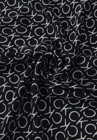 Black fabric featuring a repeating pattern of white "CK" letters, soft texture, draped in a spiral formation.