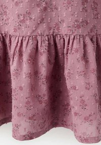 Rožnato blago z vzorcem cvetlic in nabranim robom. Vzorci vključujejo majhne cvetove in liste, kar ustvarja nežan videz. Mehko, lahko blago.