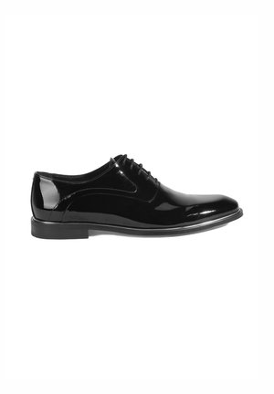 Chaussure habillée en cuir noir avec une finition laquée brillante, à lacets et à bout arrondi. Elle présente une semelle noire lisse et basse.