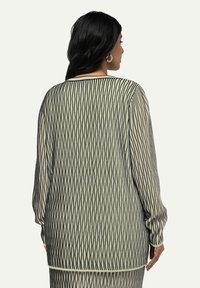 Mustat ja kermahohtoiset pitkähihaiset neuleet, joissa on teksturoitu timanttikuvio, pyöreä kaula-aukko ja rento istuvuus, takanäkymä.