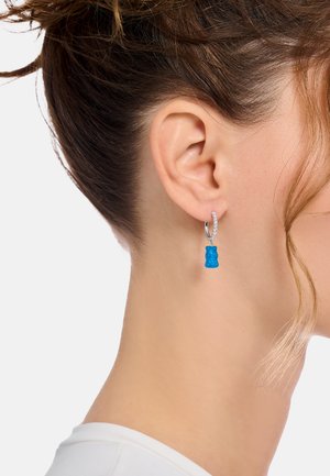 Blaue Ohrringe in Form von Gummibärchen hängen an einem silbernen Reifen und verfügen über eine strukturierte Oberfläche sowie ein glänzendes Finish.