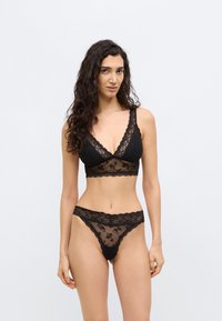 Black lace lingerie set featuring a bralette with a deep V-neck and floral patterns, paired with matching sheer lace panties.