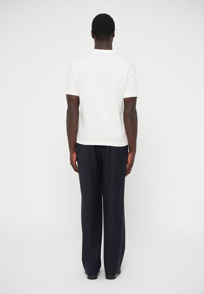 Λευκό κοντομάνικο μπλουζάκι συνδυασμένο με μπλε παντελόνια με λεπτές ρίγες, με ίσια κοπή και λεία υφή υφάσματος.