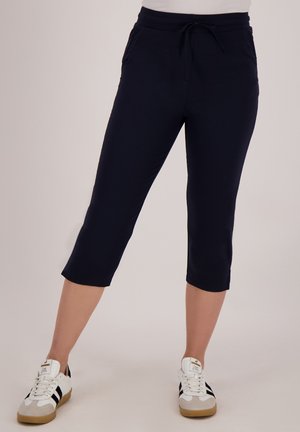 Navyblauwe capri-broek met een trekkoord in de taille, twee zijzakken en een soepel, lichtgewicht materiaal. In combinatie met witte sneakers.