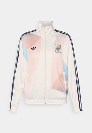 Weiße Sportjacke mit hohem Kragen, ausgestattet mit pastellfarbenen geometrischen Mustern in Pink und Blau, Adidas-Logo und marineblauen Streifen.