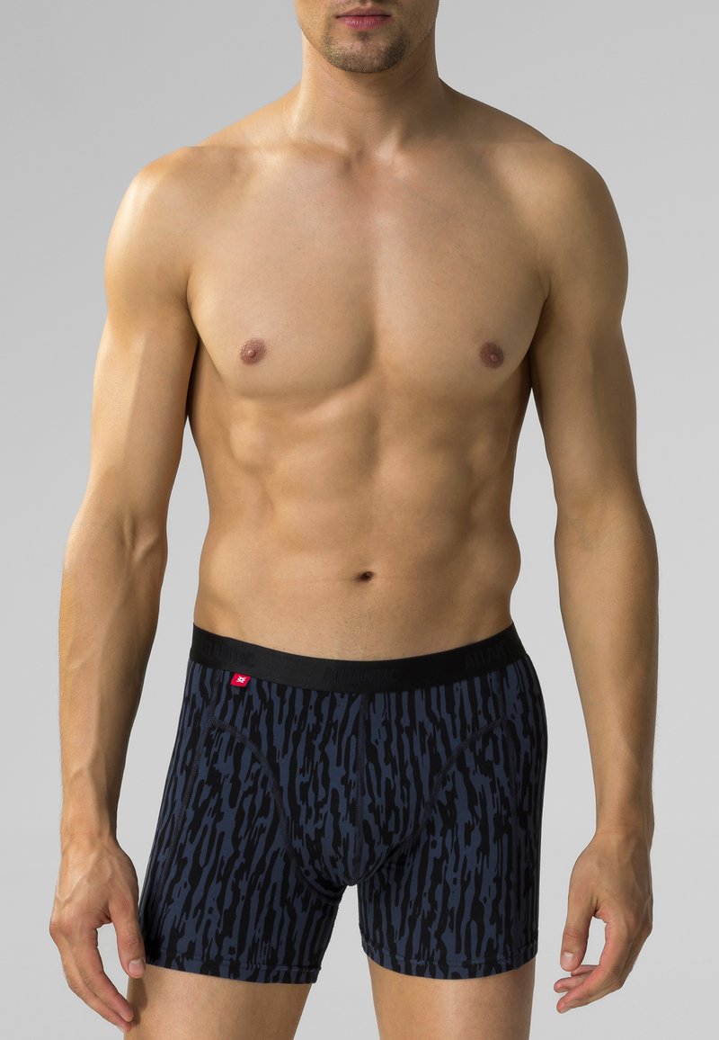 Męskie bokserki w ciemnoniebieskim kolorze z kontrastowym czarnym abstrakcyjnym wzorem. Posiadają czarny elastyczny pas z logo marki w czerwonym kolorze.