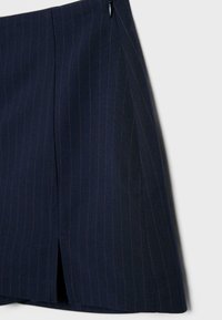 Temno modra krilo s tankimi navpičnimi črtami, z razporkom spredaj in nežnimi gubami na enostavni svetli podlagi.