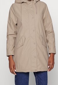 Beige hoodie-jack met knoopsluiting, voorzakken en elastische trekkoorden. Gemaakt van een gladde, waterafstotende stof.