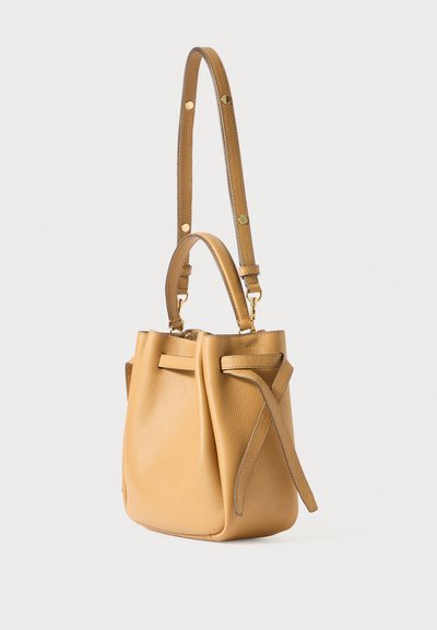 Τσάντα κουβά από υφή μουστάρδας, με επάνω χερούλι και μακρύ ρυθμιζόμενο λουρί, με μινιμαλιστικές λεπτομέρειες και ραφές.