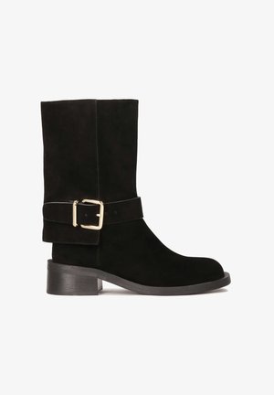 Bottines en daim noir avec un bout arrondi, un talon bloc de hauteur intermédiaire et une large sangle dotée d'un détail de boucle en or.