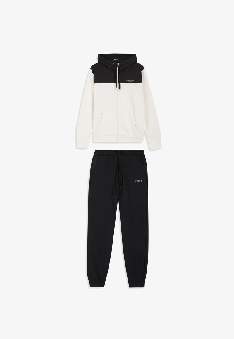 Tuta in due pezzi composta da una felpa con cappuccio bianca con zip, cappuccio e spalle nere, abbinata a pantaloni della tuta neri. Entrambi con dettagli del marchio.