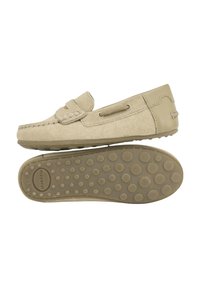 Mocasines de ante beige con puntera redondeada, costuras decorativas y cordones laterales. Suela de goma texturizada con patrones de agarre circulares.