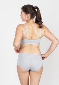 Grijze naadloze draadloze beha en bijpassende slipjes, gemaakt van zacht materiaal. De beha heeft verstelbare bandjes en een eenvoudig ontwerp, zonder zichtbare naden.