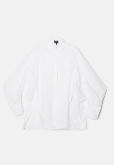 Camisa de algodão branca com colarinho clássico, mangas longas e corte reto com fendas laterais. Punhos com botões e textura suave.