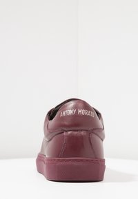 Burgundy leather sneaker with rounded design, textured rubber sole, and contrasting white printed logo "ANTONY MORATO" on heel.