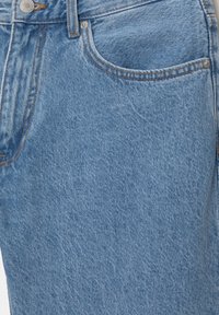 Jupe en jean bleu clair avec poches avant, passants pour ceinture et fermeture à bouton argenté.