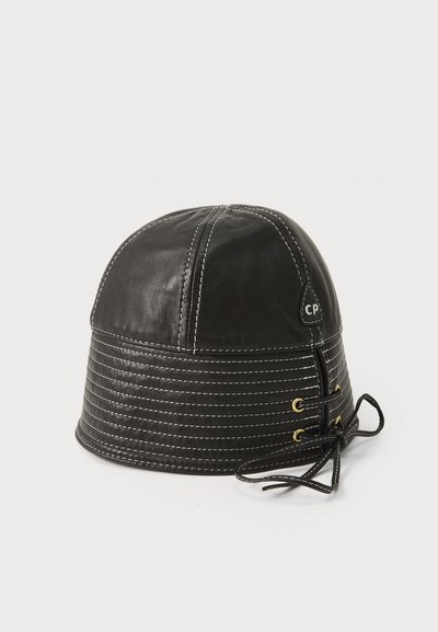 Chapeau seau en cuir noir avec une bande cousue, un corps texturé et un lacet réglable sur le côté avec des oeillets dorés.