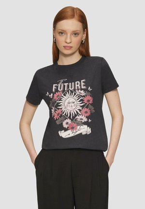 Zwarte katoenen t-shirt met een grafisch ontwerp van een zon, bloemen in het roze, en de tekst "De TOEKOMST is helder." Korte mouwen en ronde hals.