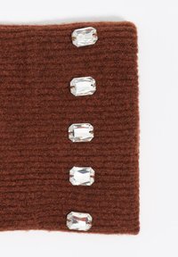 Tela marrón de punto con cinco piedras preciosas rectangulares y transparentes colocadas verticalmente a lo largo de un borde, mostrando textura y adorno.